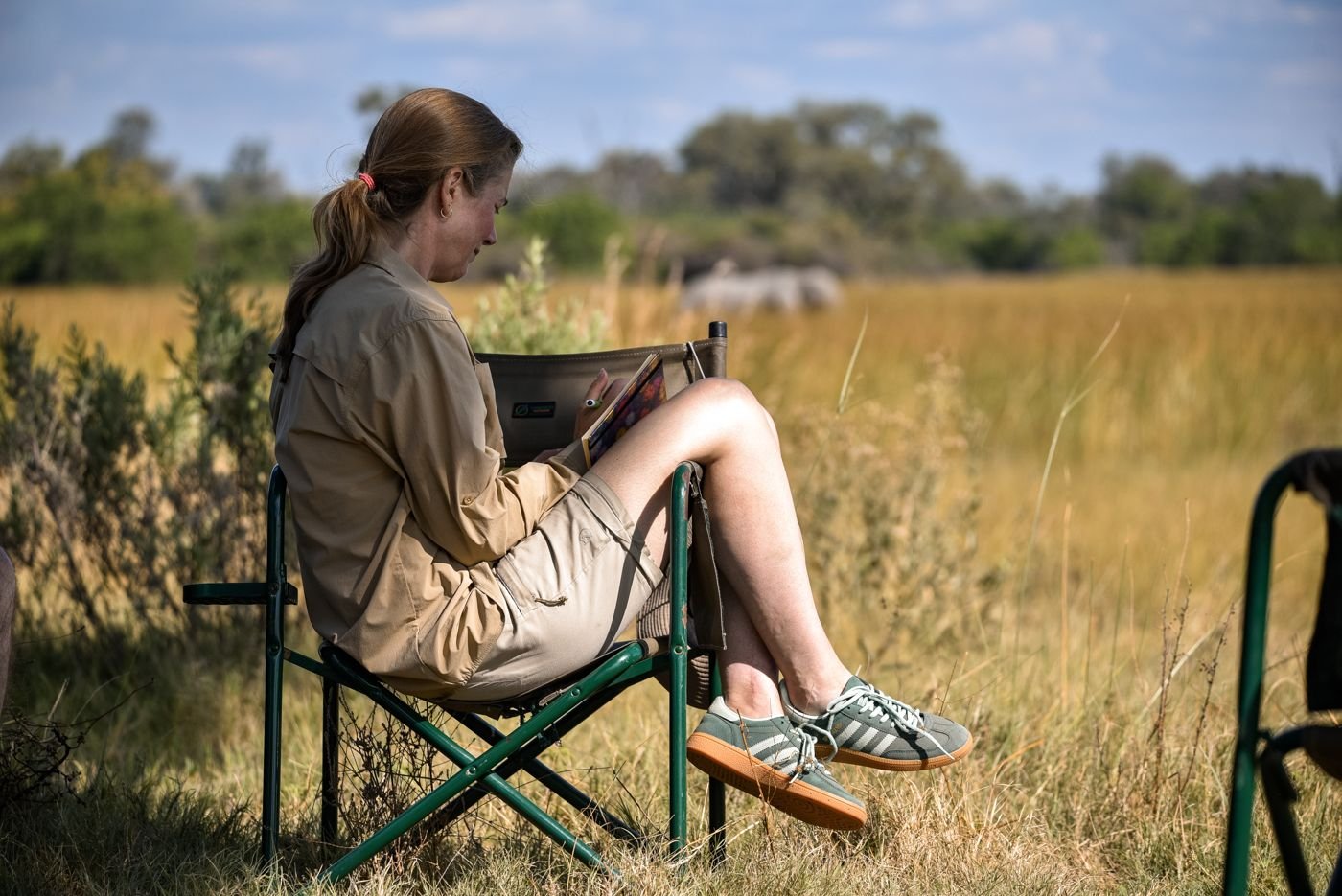 A participant writing in her journal, with an elephant grazing in the background